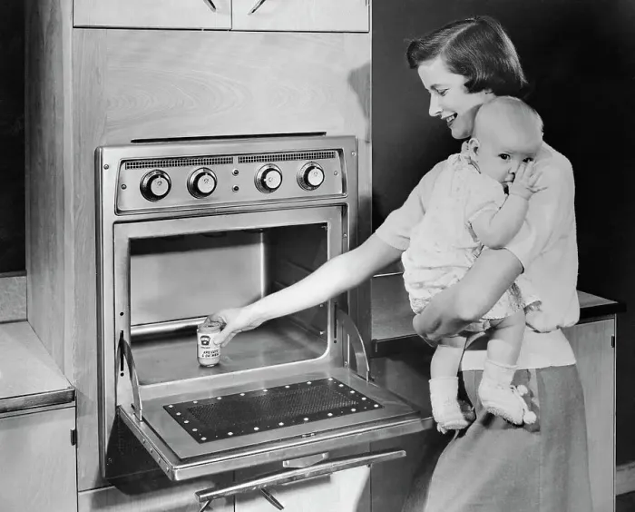 Framed Print : Woman with Baby Heating Up Food in New Oven Framed Print : Woman with Baby Heating Up Food in New Oven