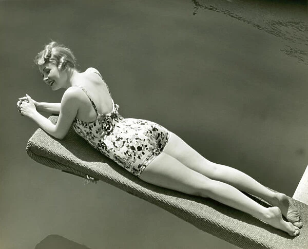 Woman in bathing suit lying on diving board