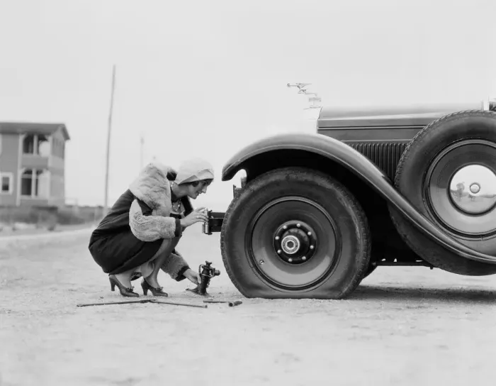 Framed Print : Woman changing flat tire on car Framed Print : Woman changing flat tire on car