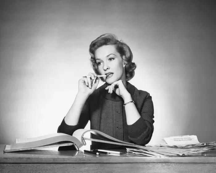 Framed Print : Woman chewing on pencil, book open in front of her Framed Print : Woman chewing on pencil, book open in front of her