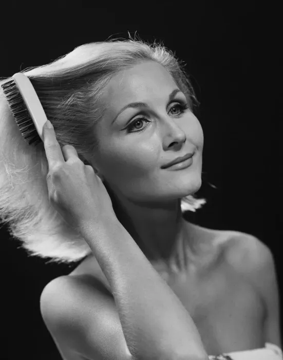 Framed Print : Woman combing hair against black background, close-up