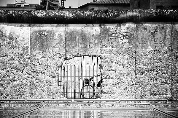 Woman cycling by a part of the Berlin Wall