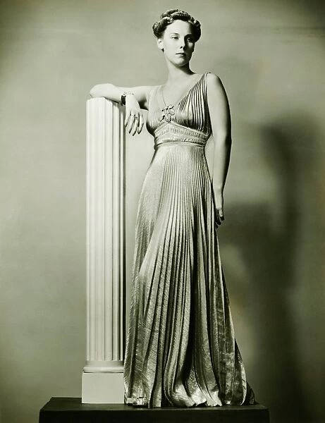 Woman in evening gown posing by column, (B&W), portrait