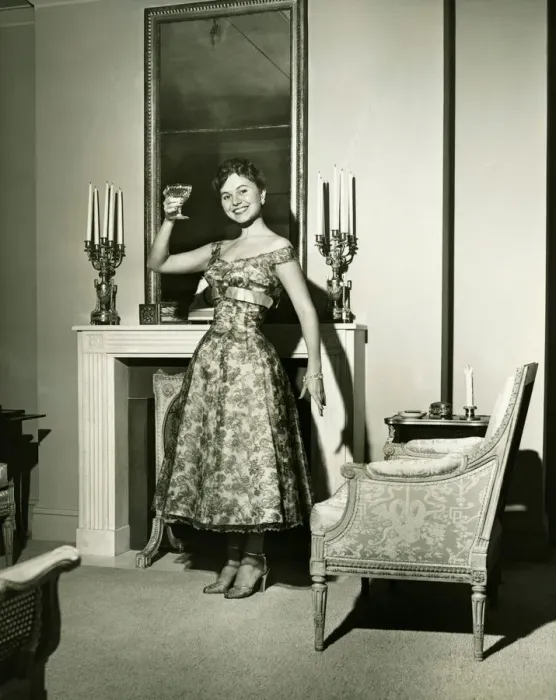 Framed Print : Woman in evening gown toasting by fireplace, (B&W), portrait Framed Print : Woman in evening gown toasting by fireplace, (B&W), portrait