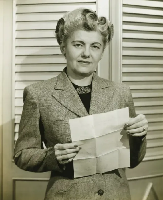 Framed Print : Woman in fashionable suit holding sheet of paper, indoors, (B&W) Framed Print : Woman in fashionable suit holding sheet of paper, indoors, (B&W)