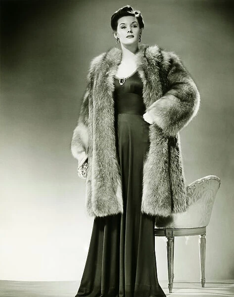 Woman in fur coat posing in studio, (B&W), portrait