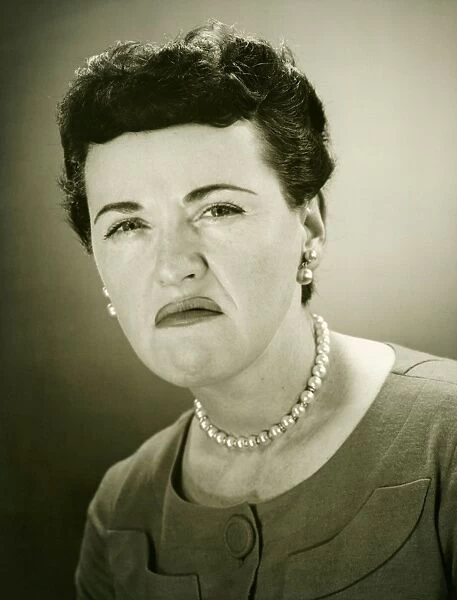 Woman grimacing in studio, (B&W), close-up, portrait