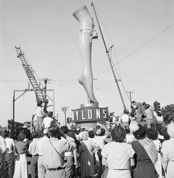 Framed Print : Woman Hoisted Next to a Giant Plaster Leg Framed Print : Woman Hoisted Next to a Giant Plaster Leg