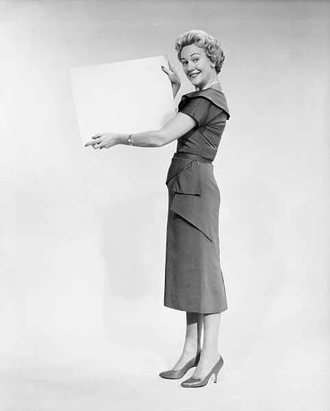 Woman holding blank piece of paper, portrait, studio shot