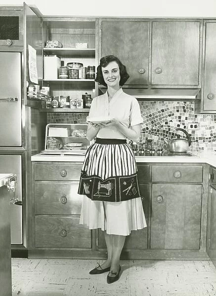 Woman holding pie, posing in kitchen, (B&W), portrait