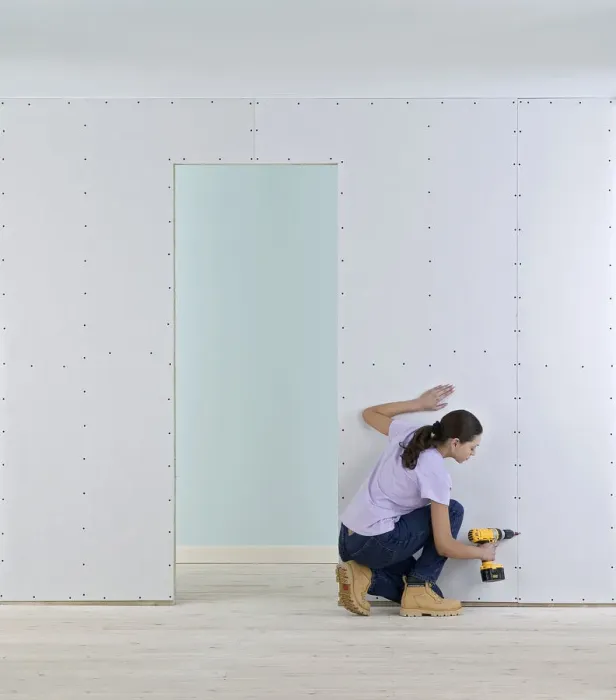 Framed Print : Woman holding screwdriver to wall of plasterboard Framed Print : Woman holding screwdriver to wall of plasterboard