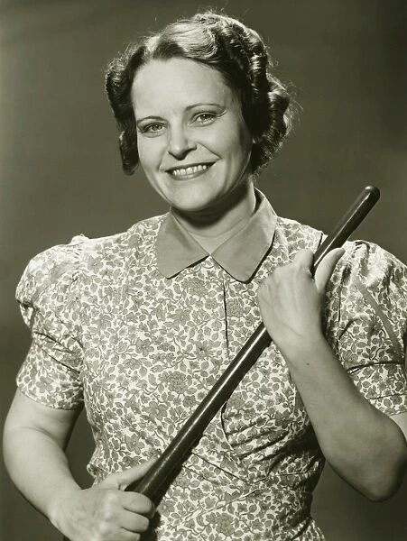 Woman holding stick, posing in studio, (B&W), portrait