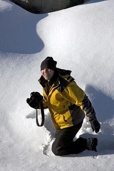 Woman kneeling in the snow holding a camera, Jasper National Park, Alberta, Canada