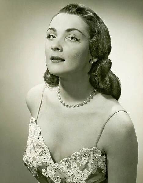 Woman in lace evening gown posing in studio, (B&W), portrait