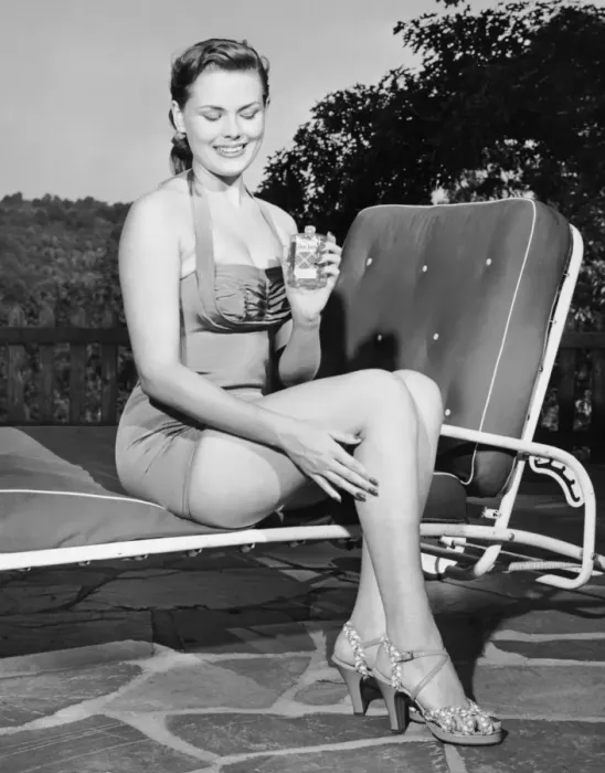 Framed Print : Woman on lawn chair applying oil to her legs