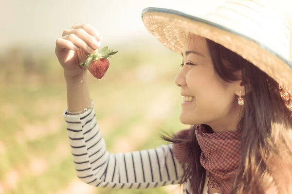 Woman looking at strawberry with happy face