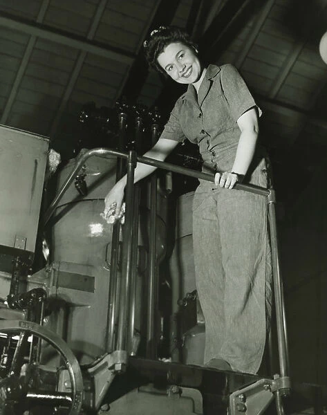 Woman operating machine in factory, (B&W), portrait, low angle view
