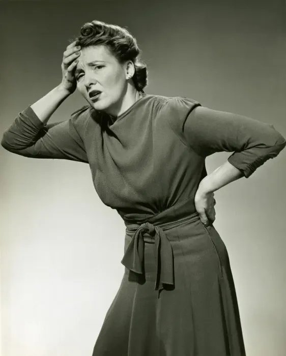 Framed Print : Woman in pain clutches head and back