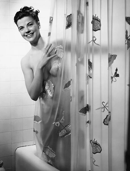 Woman peering through shower curtain, (B&W), portrait