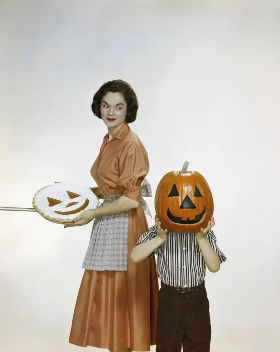 Framed Print : Woman with pie looking at child holding halloween pumpkin, smiling Framed Print : Woman with pie looking at child holding halloween pumpkin, smiling