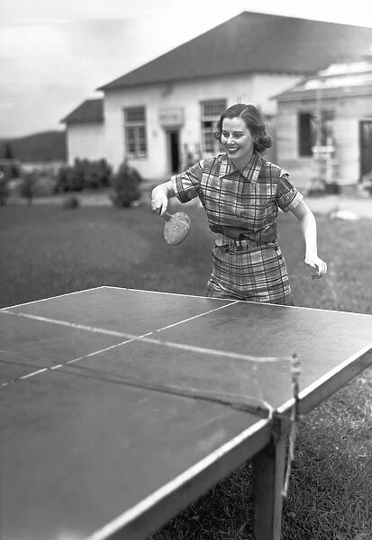 Woman playing table tennis in garden, (B&W)