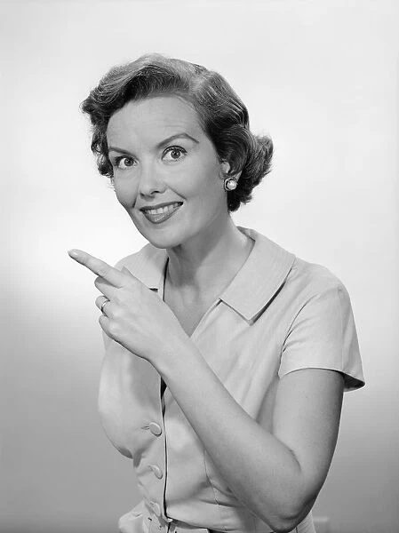 Woman pointing, studio portrait