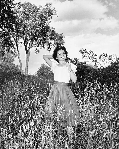Woman posing on meadow, (B&W), portrait