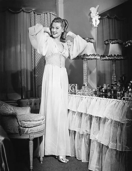 Woman posing by vanity table in opulent bedroom, (B&W), portrait