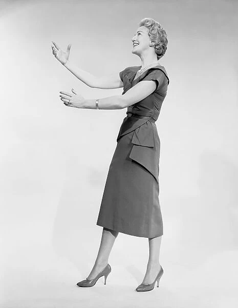 Woman raising arms, studio shot, side view