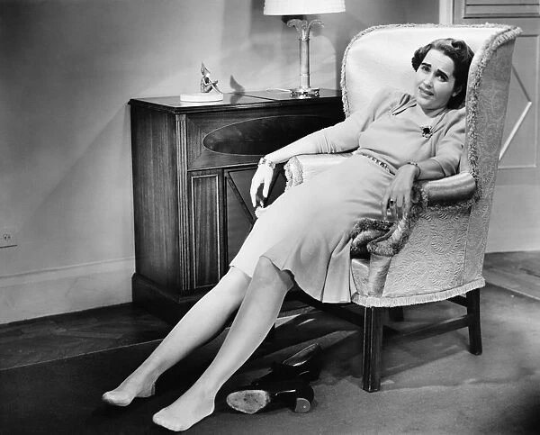 Woman reclining in armchair, exhausted, (B&W)