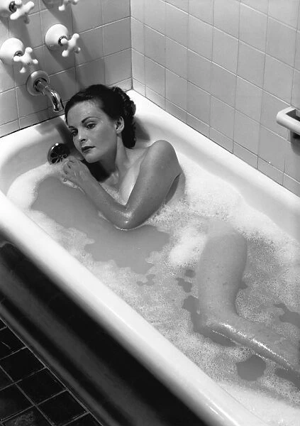 Woman relaxing in bath, (B&W), elevated view