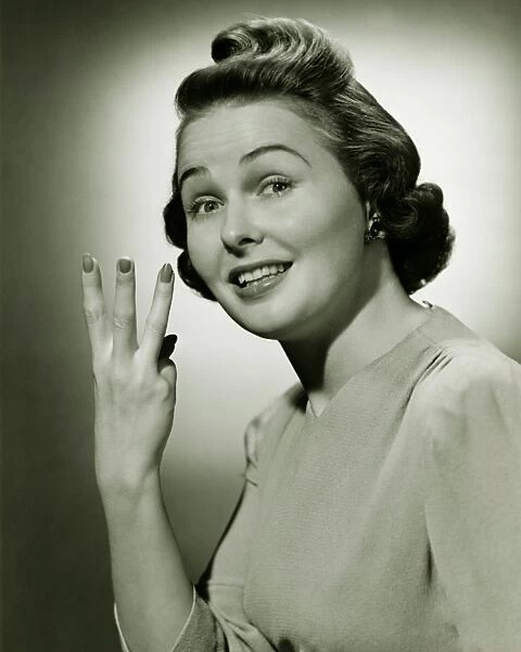 Woman showing three fingers in studio, (B&W), portrait
