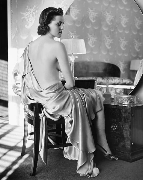 Woman in silk bathrobe sitting in front of vanity table (B&W)