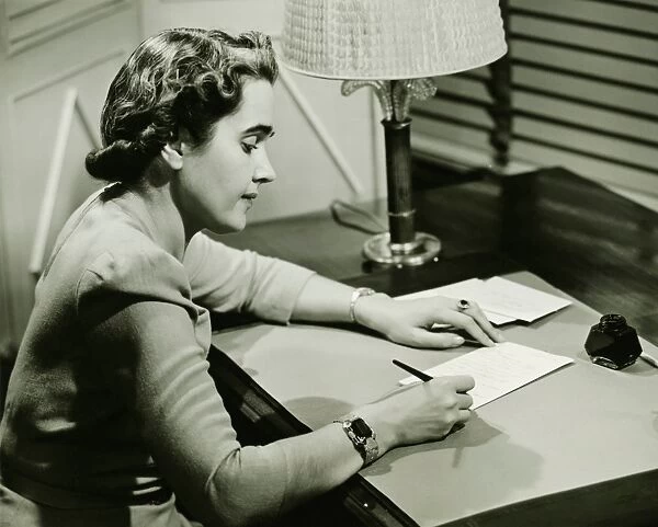 Woman sitting at desk, writing, (B&W)