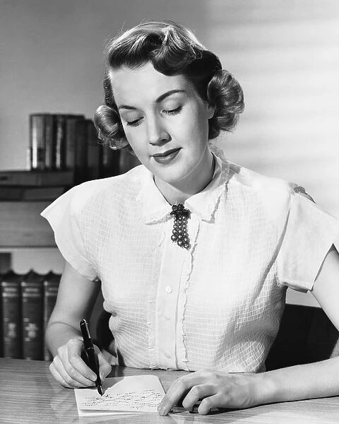 Woman sitting at desk, writing note