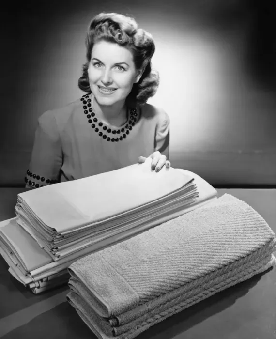 Framed Print : Woman sitting at pile of ironed linen and towels (B&W), portrait Framed Print : Woman sitting at pile of ironed linen and towels (B&W), portrait