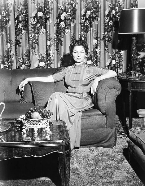 Woman sitting in rich living room, (B&W)