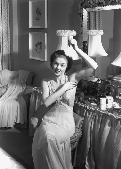 Framed Print : Woman sitting at vanity table, applying cosmetics, (B&W) Framed Print : Woman sitting at vanity table, applying cosmetics, (B&W)