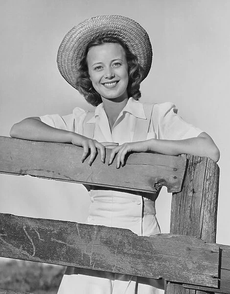 Woman smiling while leaning on a wooden fence