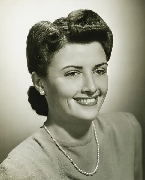 Woman smiling in studio, (B&W), close-up
