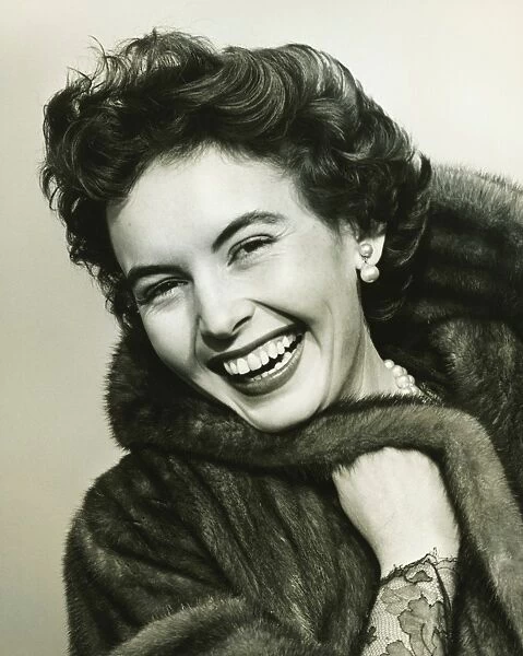 Woman smiling in studio, (B&W), portrait