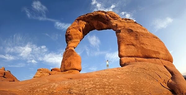 Woman standing under Delicate Arch natural stone arch, Arches-Nationalpark, near Moab, Utah, United States