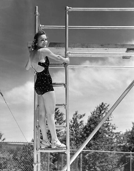 Woman standing on ladder at springboard, (B&W)