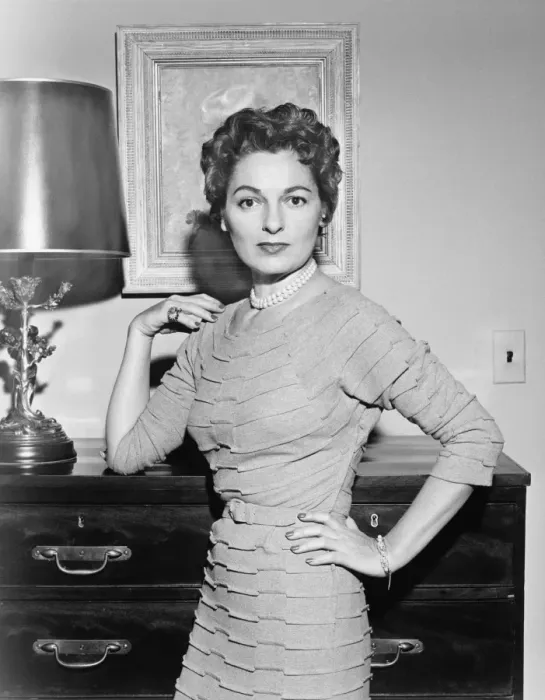 Framed Print : Woman standing in living room with hand on cabinet, (B&W)