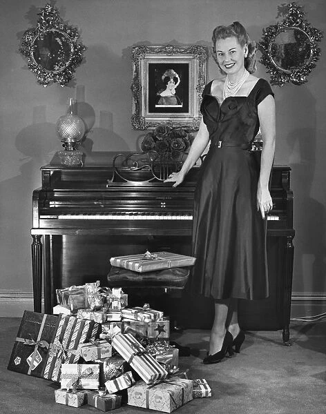 Woman standing by piano & presents