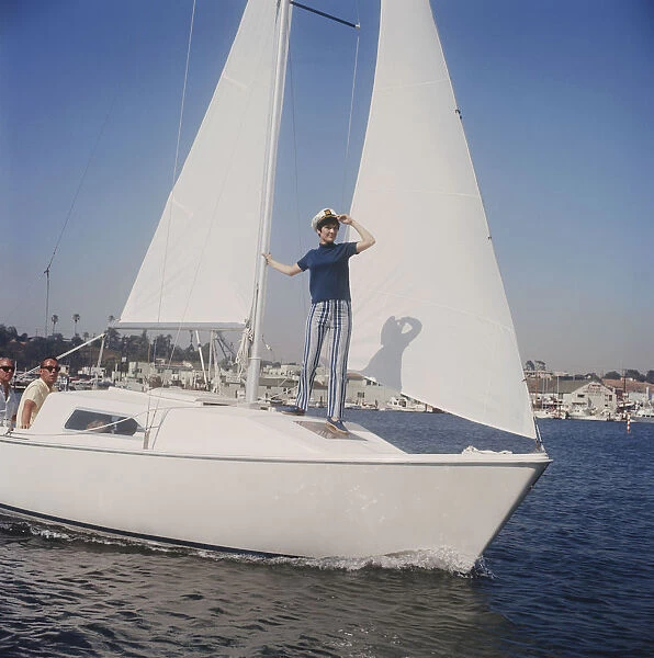 Woman standing on sailing boat, two men in background
