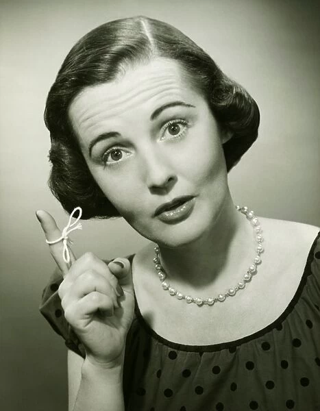 Woman with string tied around finger in studio, (B&W), (Close-up), (Portrait)