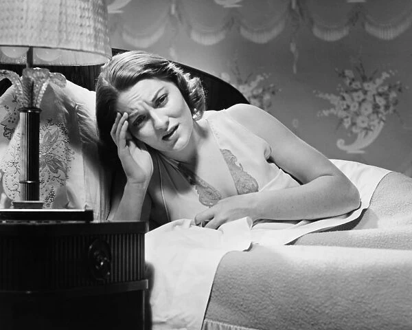 Woman suffering headache lying in bed (B&W)