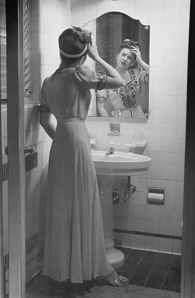 Woman suffering headache standing in front of bathroom mirror, (B&W)