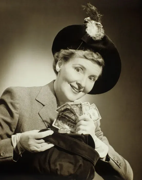 Framed Print : Woman in suit and fashionable hat standing taking money out of bag in studio, (B&W), portrait Framed Print : Woman in suit and fashionable hat standing taking money out of bag in studio, (B&W), portrait